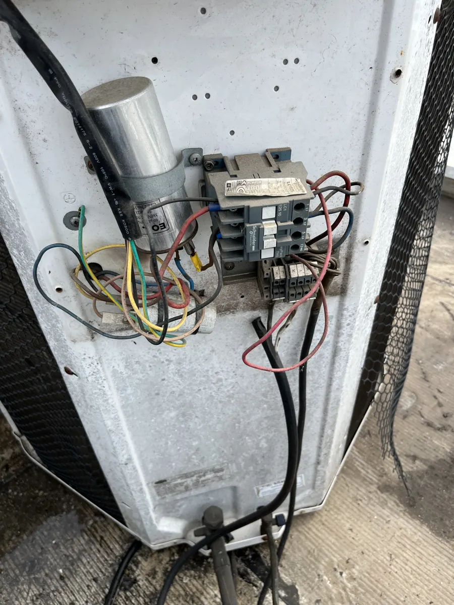 Painel elétrico da condensadora com o capacitor (cilindro metálico) e a contatora, em manutenção corretiva feita pela Watt Soluções Climatização e Elétrica